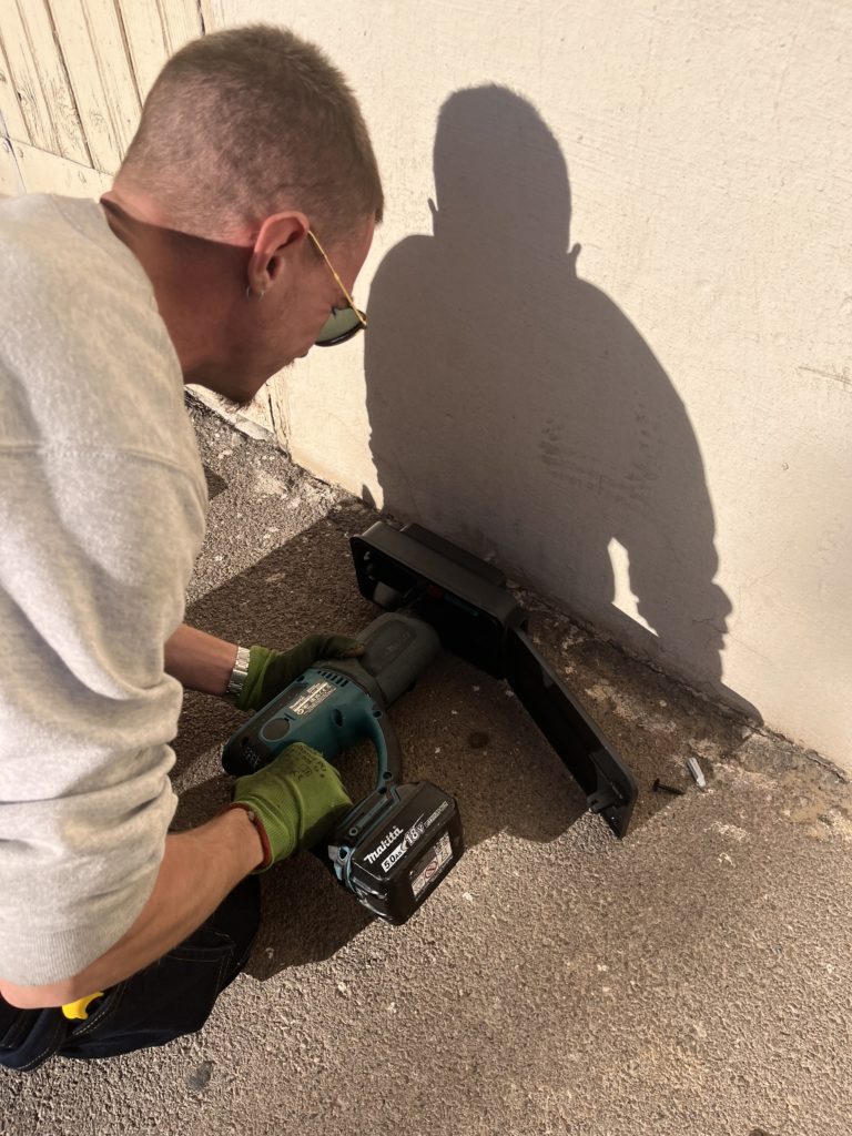 Pour lutter contre les rats, le technicien installe un poste sécurisé qui est fixé au mur